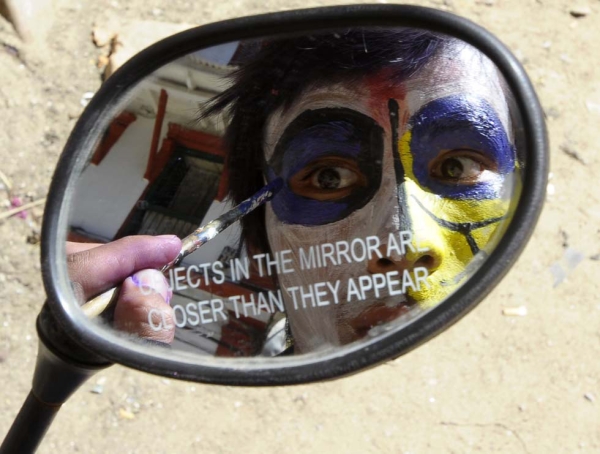 A Nepalese reveler uses a motorcycle mirror to paint his face during Holi celebrations in Kathmandu, Nepal on March 26, 2013. (Prakash Mathema/AFP/Getty Images)