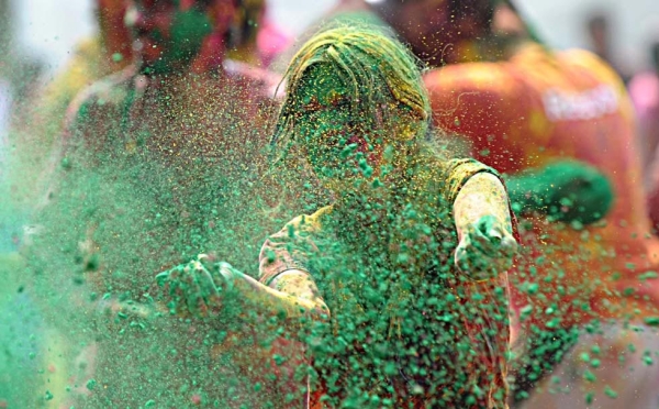 A woman scatters vibrant green powder during Holi festivities in Hyderabad, India on March 27, 2013. (Noah Seelam/AFP/Getty Images)