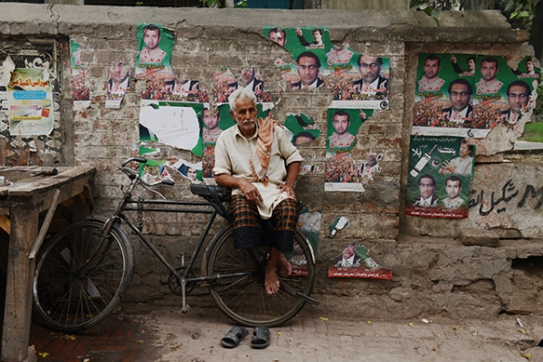 An ice vendor sits on his bicycle in front of a wall covered with political posters in Lahore, Pakistan on May 10, 2013. (Roberto Schmidt/AFP/Getty Images)