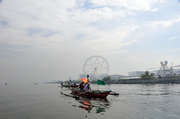 Fishermen cruise serenely through a mall and entertainment park along the bay in Manila, Philippines on May 31, 2013. (Veejay Villafranca/Getty Images))