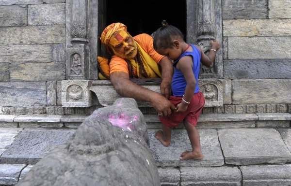 A Hindu sadhu, or holy man, plays with a small child at the Pashupatinath Temple in Kathmandu on July 31, 2013. (Prakash Mathema/AFP/Getty Images)