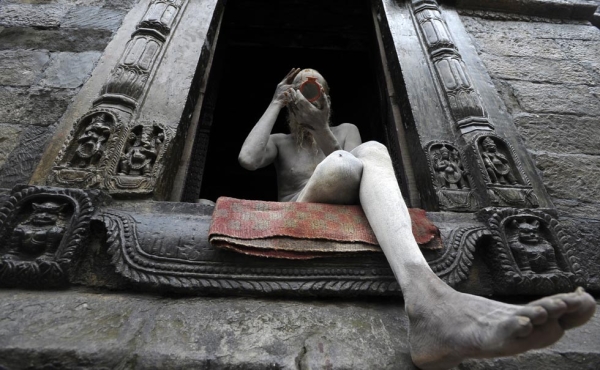 A Hindu sadhu (holy man) smears coloured paste onto his face at the Pashupatinath Temple in Kathmandu on July 31, 2013. Dozens of sadhus live around the temple devoting their life to Lord Shiva, the Hindu god of destruction. (Prakash Mathema/AFP/Getty Images)