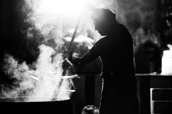 A cook prepares a large feast in giant pots billowing with steam in Tiruvannamalai, India on November 22, 2013. (Vinoth Chandar/Flickr)