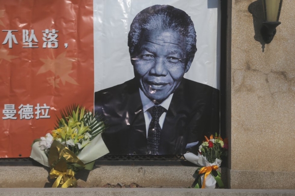 Flowers are placed in front of an image of former South African president Nelson Mandela at the Embassy of South Africa in Beijing, China on December 6, 2013. (ChinaFotoPress/Getty Images)