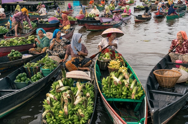 Women maneuver their produce-laden boats at the Lok Baintain floating market in South Kalimantan, Indonesia on December 31, 2013. (killerturnip/Flickr)