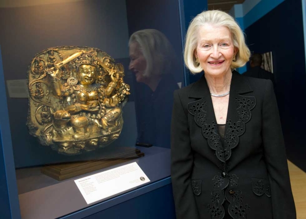 Exhibition supporter Ann Kinney stands beside the Dhumavati Sridevi gilt copper relief sculpture that she and her husband gifted to the Asia Society Museum Collection. (Elena Olivo/Asia Society)