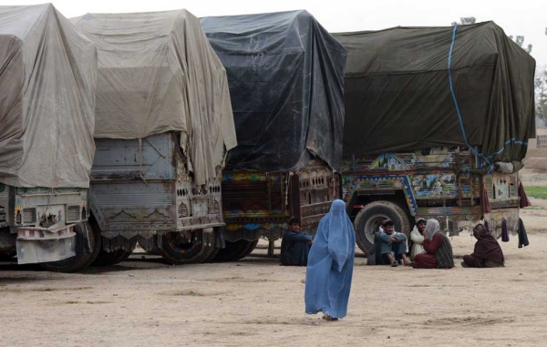 A woman walks past trucks carrying ballot boxes and election material in Kandahar on April 3, 2014. (Banaras Khan/AFP/Getty Images)