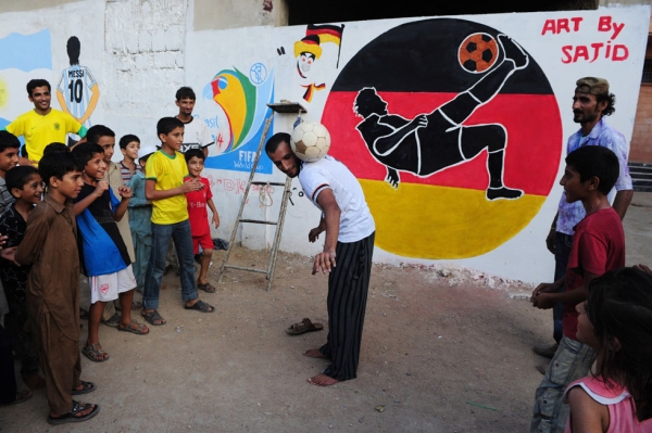 A Pakistani fan demonstrates his skills in front of a mural celebrating the World Cup painted on the wall of a house in Karachi on June 12, 2014. (Asif Hassan/AFP/Getty Images)