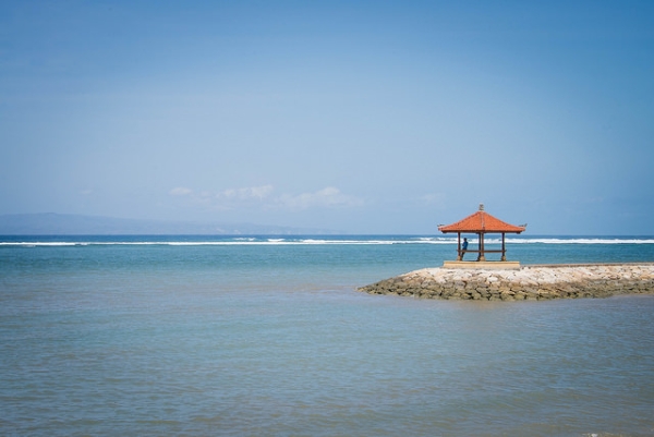 A man stands under a gazebo overlooking the ocean at Sanur Beach in Bali, Indonesia on September 11, 2014. (Darien Graham-Smith/Flickr)