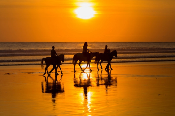 Horseback riders make their way across Legian Beach, Indonesia on September 13, 2014. (Tom Roeleveld/Flickr)
