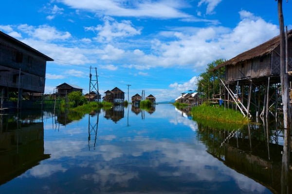 White clouds, homes on stilts, and the vast blue sky are duplicated in Myanmar's reflective waters on June 18, 2014. (Lim Ashley/Flickr) 