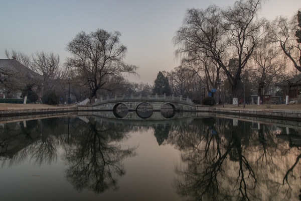 A bridge flanked by trees forms a serene reflection in a pond in Beijing, China on January 8, 2015. (Jens Schott Knudsen/Flickr)