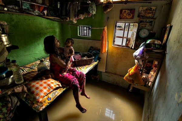 A mother plays with her child in a flooded room, near the banks of the Ganges River in Kolkata, India. Photograph by Joydeep Mukherjee. (Smithsonian.com)