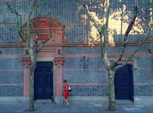 A woman in red is photographed as she passes between two doors and two barren tree trunks in Shanghai, China on September 14, 2015. (Lawrence Wang/Flickr)