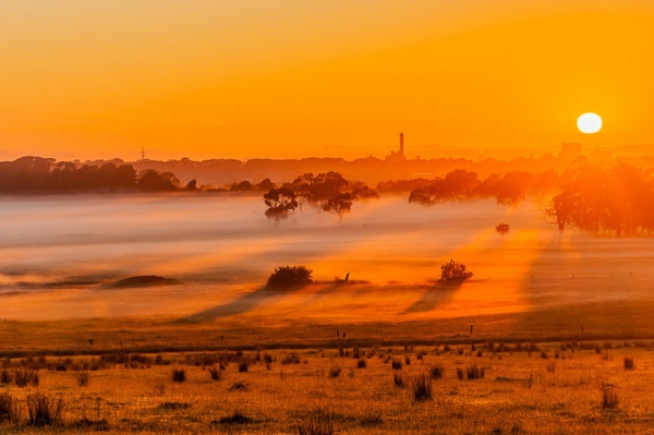 The rising sun casts an orange glow over the fields and trees in Victoria, Australia on November 9, 2015. (Graham Hartle/Flickr)