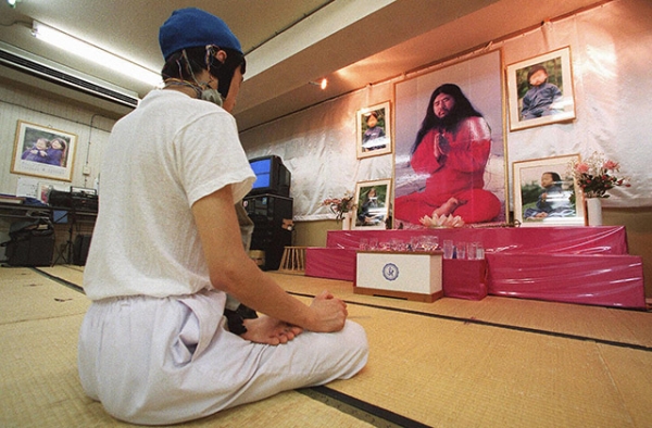 An Aum Shinrikyo follower meditates before portraits of leader Shoko Asahara and his two sons posted on an altar at a seminary of a Tokyo building on August 11, 1999. (Toru Yamanaka/AFP/Getty Images)