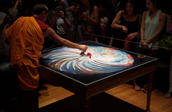 A monk ceremoniously swirls together the sand as part of the deconstruction of the mandala in Houston, Texas on August 23, 2015. (Tiffany Chen/Asia Society)