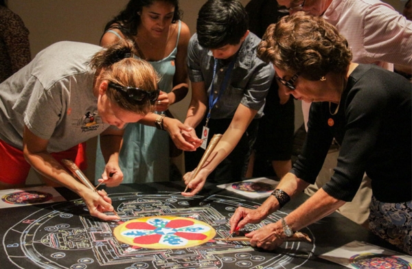 Museum-goers try their hand at using the chakpur, a traditional Tibetan tool used to create sand mandalas, at Asia Society Texas on August 25, 2016. Asia Society Texas hosted Tibetan Buddhist monks from Drepung Loseling Monastery in India to create the mandala in addition to other performances. (Asia Society/Nikki Tripp)