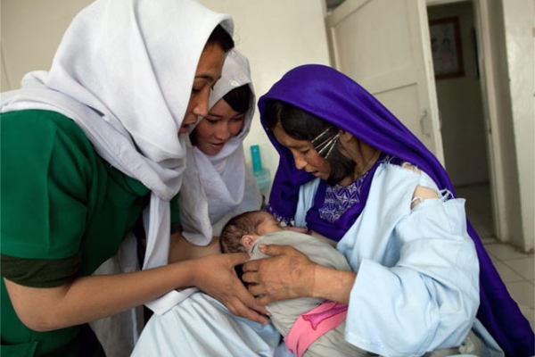 Bamiyan, 2009: An Afghan midwife helps a mother nurse her newborn baby at the Bamiyan Provincial hospital. Photo featured in the ART WORKS exhibition "Women Between Peace and War: Afghanistan," on view at Asia Society New York Oct. 3, 2013. (Paula Bronstein) 