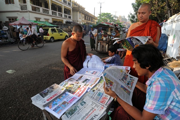 Buddhist monks read newspapers at a stall near the Shwedagon pagoda in Yangon on May 9, 2014. (Soe Than WIN/AFP/Getty Images)