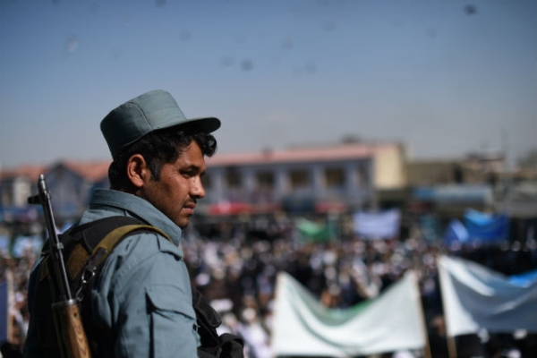 An Afghan policeman keeps watch as clergy men attend a gathering at the Shahi Doshamshira mosque where an Afghan woman, 27, was beaten to death and her body set alight by a mob, in Kabul on March 26, 2015. (Shah Marai/AFP/Getty Images)