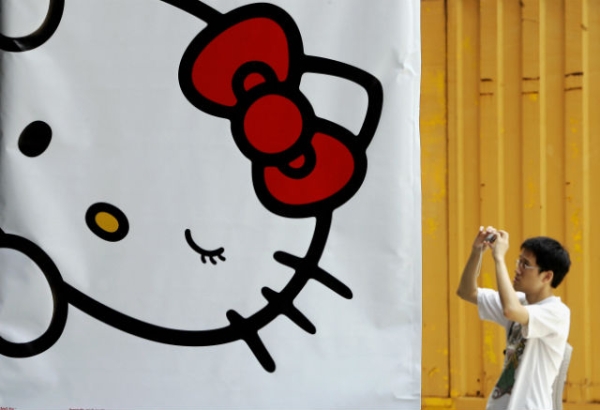 A man takes a picture next to a banner set up for an exhibition for popular animation character Hello Kitty in Hong Kong, 29 August 2005. (Phillipe Lopez/AFP/Getty Images)