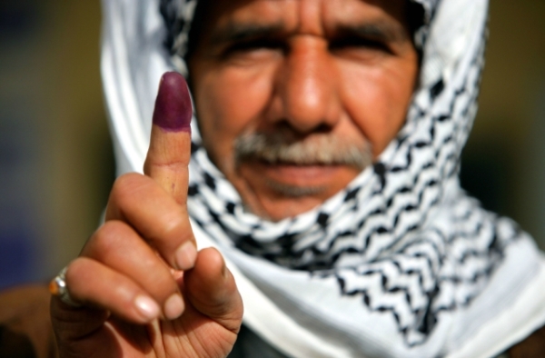 An Iraqi man in Najaf displays his finger to the camera on January 30, 2005 in Najaf, Iraq. The purple dye indicates that he has just voted in Iraq's first elections. (Brent Stirton/Getty Images)