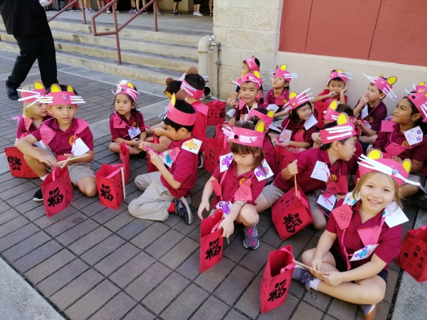 Kindergarten students wearing Year of the Rat headbands and holding red “fu” good fortune lanterns