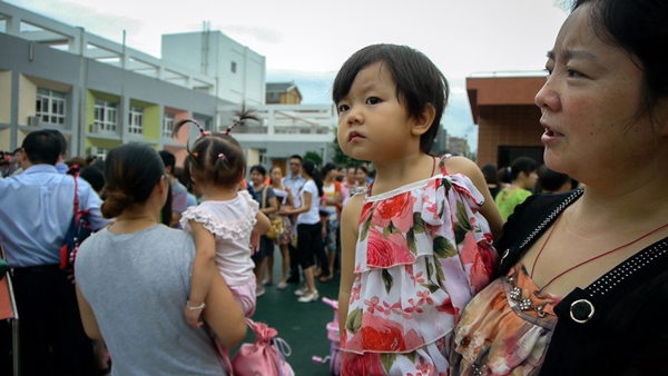 Fu Guangjun holds her daughter Jiang Yutong, 2, on the first day of preschool classes in New Beichuan. Film still from 'The Reborn of Beichuan.'