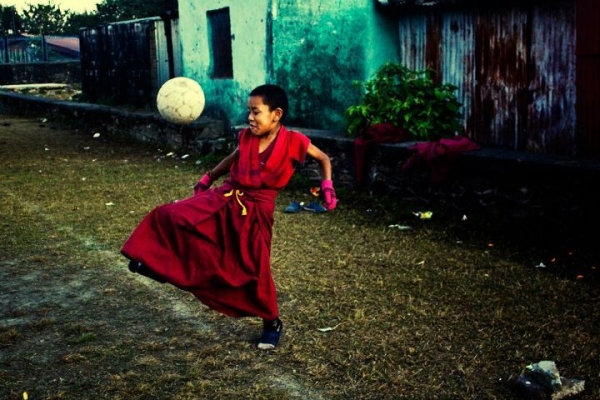 A young monk plays football in a Tibetan camp ground in Pokhara, Nepal. (Sai Abishek)