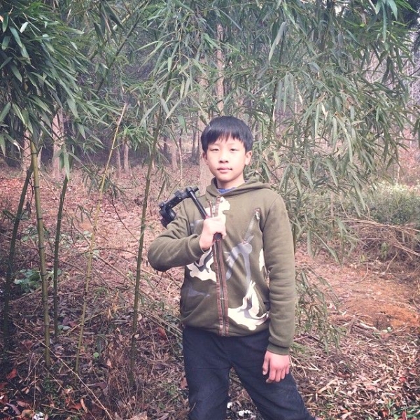 Ou Jian, Ou Ning’s nephew, insists on carrying my tripod as we climb up the hillside. (Sun Yunfan)
