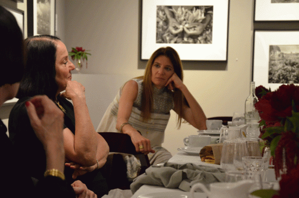 Lelia Salgado (center foreground), Sebastiao’s wife, creative partner and founder of a nonprofit to replant Brazil’s Atlantic Rainforest, listens as Sebastiao speaks at a June 4 ASSC dinner at the Peter Fetterman Gallery. In the background is Salgado’s photograph of a tea picker in Rwanda.
