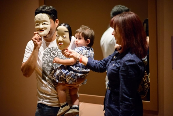 October 25 - Guests visiting the 'Traditions Transfigured' exhibition try on Noh Masks. (Photo: Jeff Fantich)