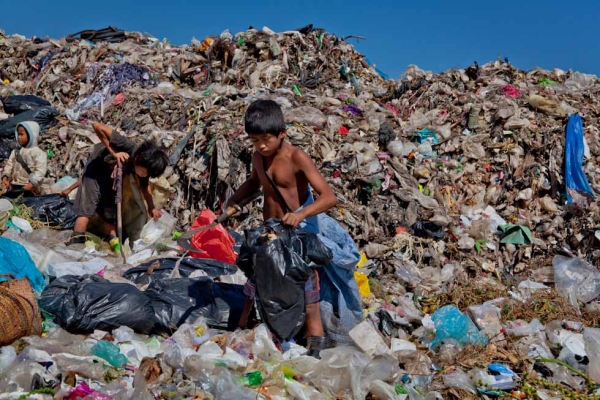 Three children work together at the dump. The child on the left is just seven years old and recently received a pair of gumboots. Fred Stockwell also provides the people of the dump with gumboots and solar-powered head lamps to avoid injury during night shifts. (Jacques Maudy)