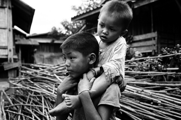 A young boy carries a toddler on his shoulders in Namtha, Laos on July 9, 2012. (HRAMIREZ/Flickr)
