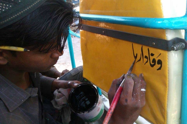 A young artist paints a verse on the back of one of the rickshaws. (Pakistan Youth Alliance)