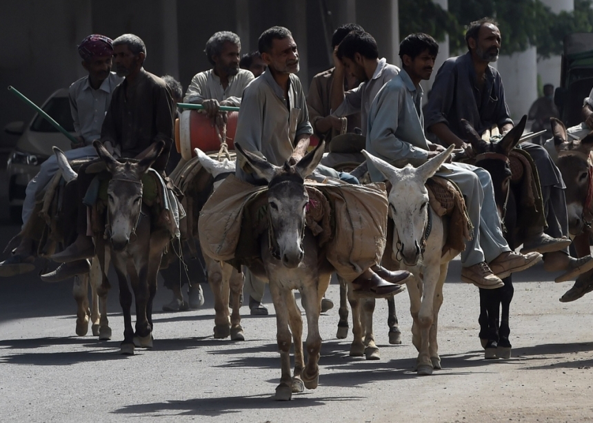   Men ride donkeys on a street during International Labor Day, in Lahore, Pakistan, May 1, 2020.