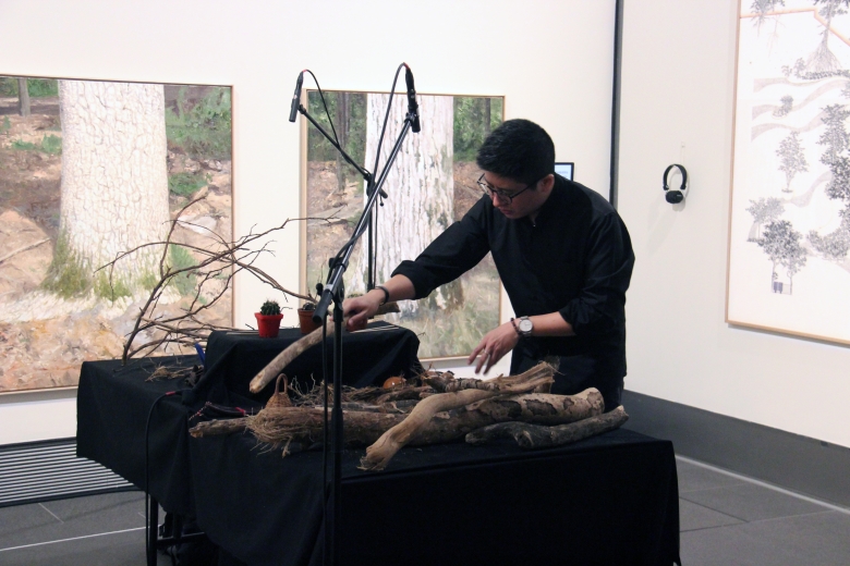 Man playing branches as an instrument in a gallery