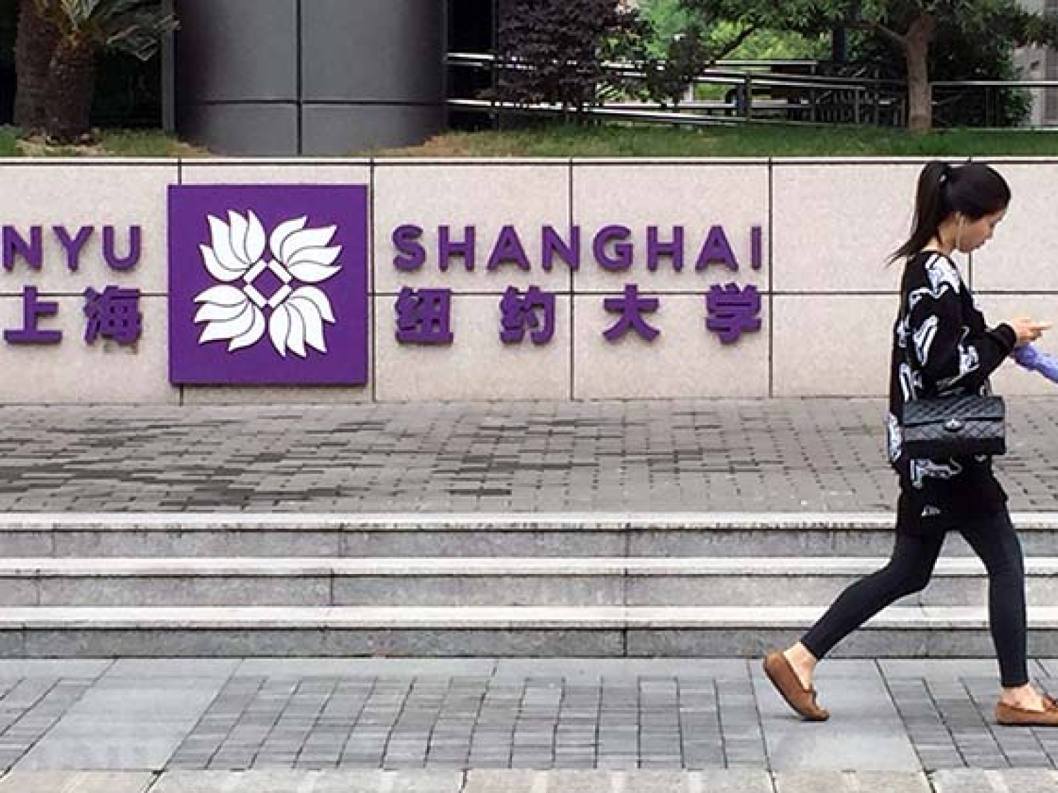 A student walks past the entrance to New York University's Shanghai campus. (Eric Fish/Asia Society)