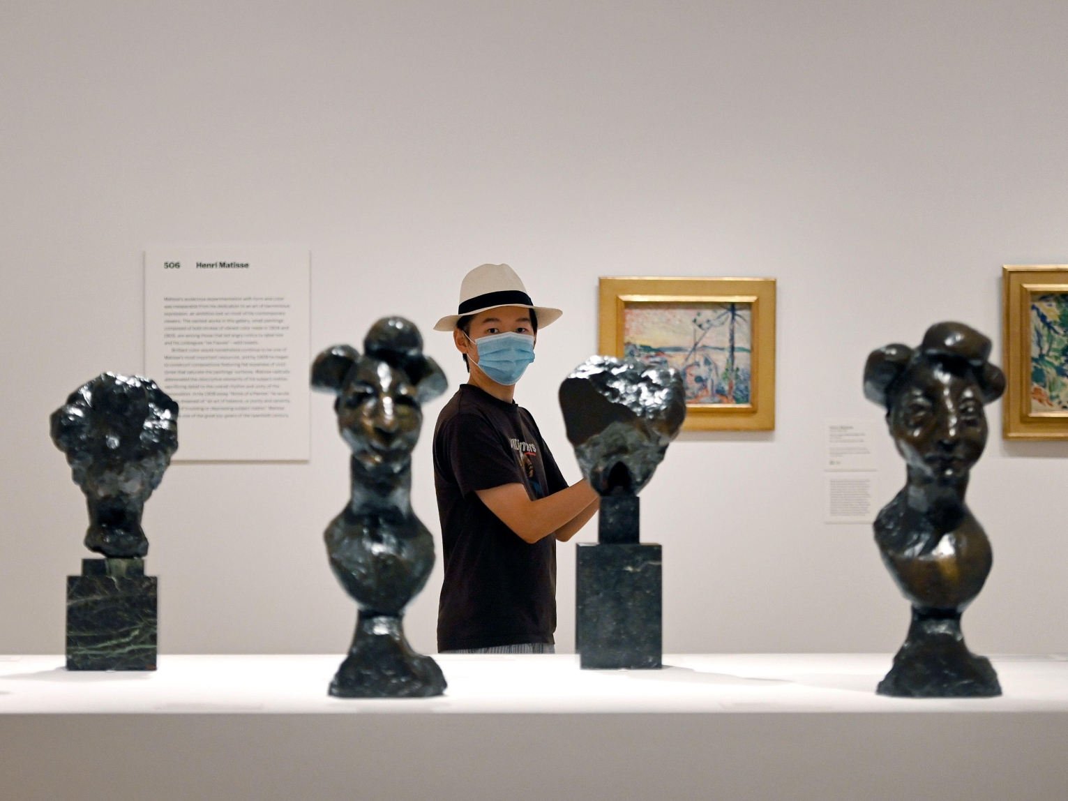 A masked museum-goer looks at art.